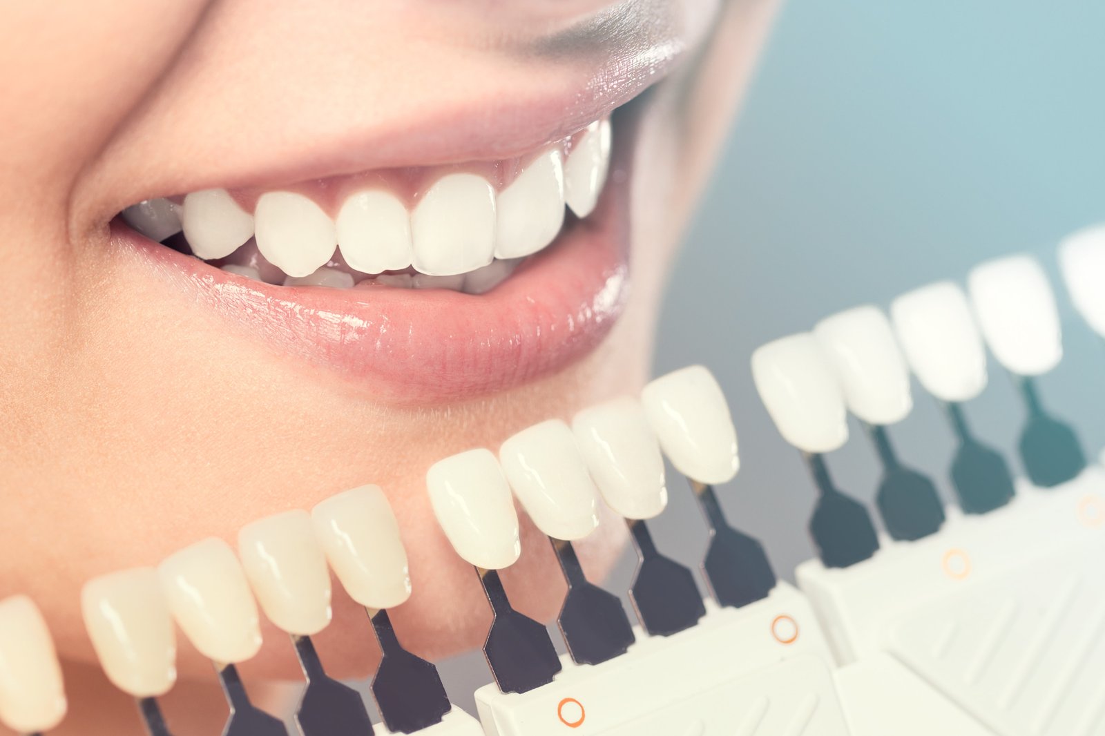 Patient smiling and checking her teeth in a mirror after a cosmetic dentistry visit